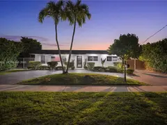 Front of the home at dusk, under the palm trees
