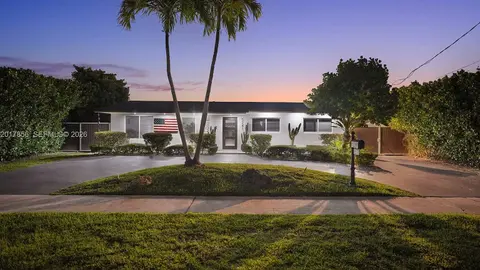 Front of the home at dusk, under the palm trees