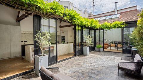 Cour pavée du bien, sous une pergola végétalisée